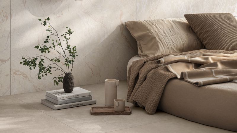 Ein modernes Schlafzimmer mit einem gemütlichen Bett in neutralen Tönen, einer dekorativen Pflanze auf einem Bücherstapel und einer stilvollen Wandlampe.