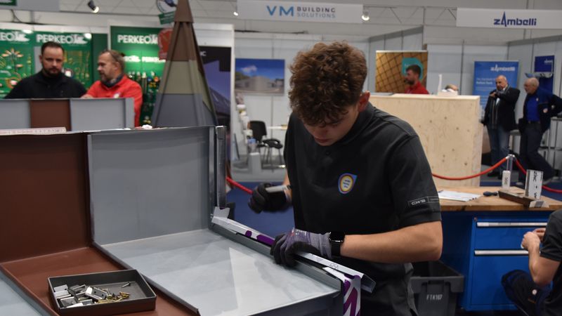 Ein junger Handwerker arbeitet konzentriert an einem Metallstück auf einer Messe.