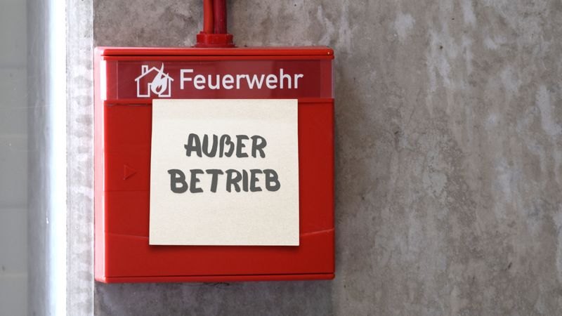Ein roter Feueralarm mit einem Zettel, auf dem "Außer Betrieb" steht.