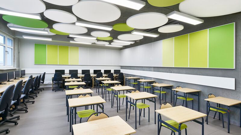 Ein modernes Zimmer mit Computerarbeitsplätzen und farbenfrohen Akustikpaneelen an der Decke und den Wänden.