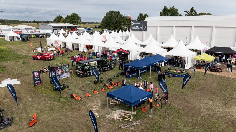 Eine Messeausstellung im Freien mit mehreren weißen Zelten und Ständen, die verschiedene Produkte präsentieren.