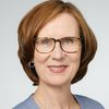 Porträt einer Frau mit Brille und kurzen braunen Haaren.