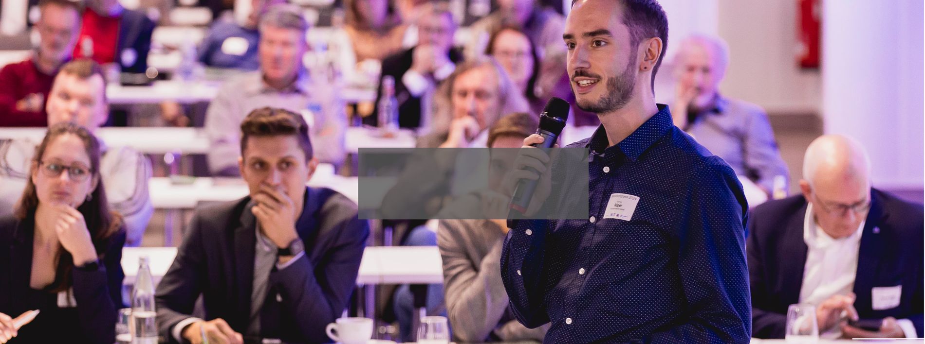 Ein Mann hält einen Vortrag auf einer Konferenz vor einem Publikum.