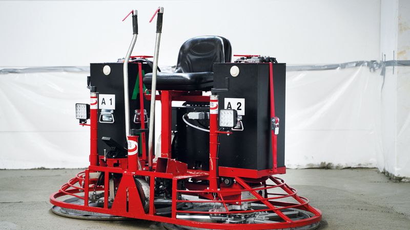 Eine rote Betonglättmaschine auf einer Baustelle, bereit zur Bearbeitung des Betonbodens.