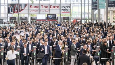 Eine große Menschenmenge betritt die Expo Real Messe in München, während sie durch die Eingangskontrollen geht.