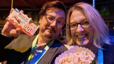 Zwei Personen halten Schokolade und Popcorn in einem Veranstaltungsort.