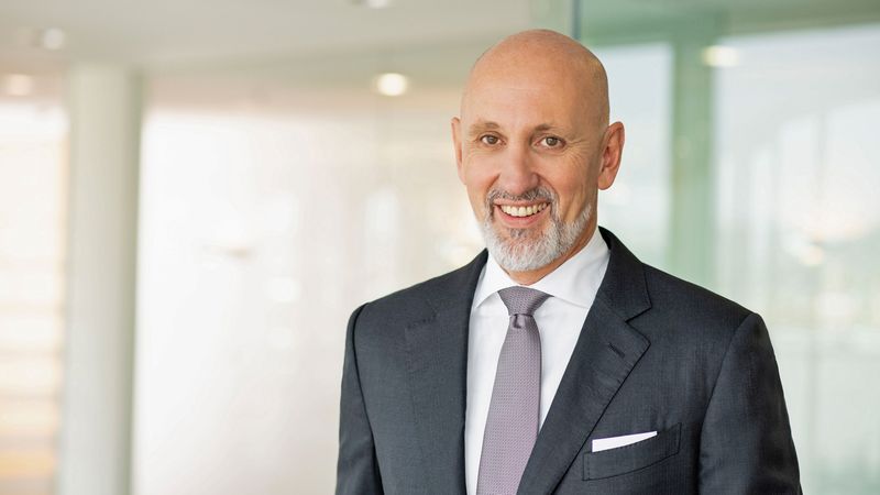 Ein lächelnder Geschäftsmann in einem Anzug steht in einem modernen Büro.