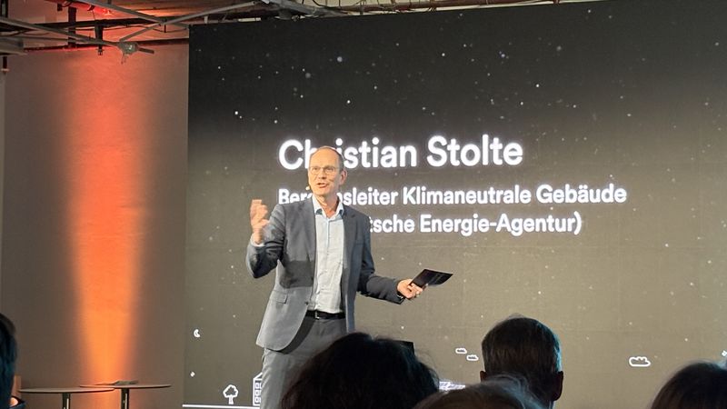 Ein Mann hält eine Präsentation über klimaneutrale Gebäude auf einer Bühne.