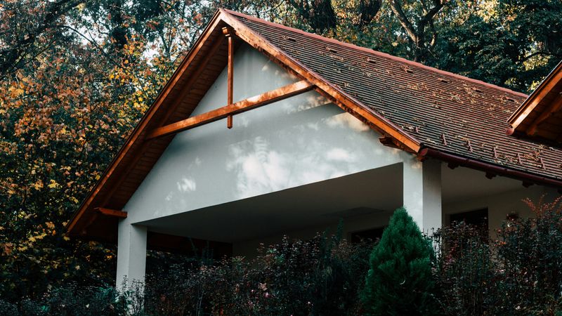 Ein Haus mit einem roten Ziegeldach, umgeben von herbstlichen Bäumen.