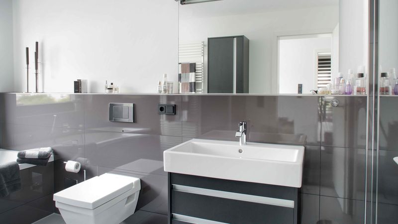 Ein modernes Badezimmer mit einem eleganten Waschbecken und einer großen Spiegelwand.