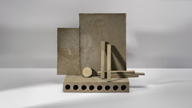 Eine Anordnung von geometrischen Formen, darunter Rechtecke, Zylinder und ein Block mit Löchern, auf einer weißen Oberfläche.