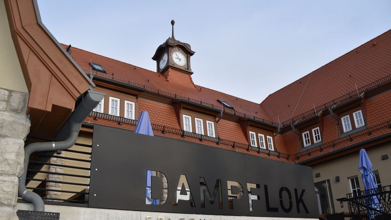 Das Bild zeigt die Erlebniswelt Dampflok in Meiningen mit einem markanten Uhrturm im Hintergrund.