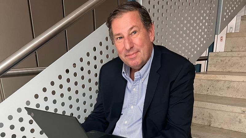 Ein Mann in einem Anzug sitzt auf einer Treppe und arbeitet an einem Laptop.