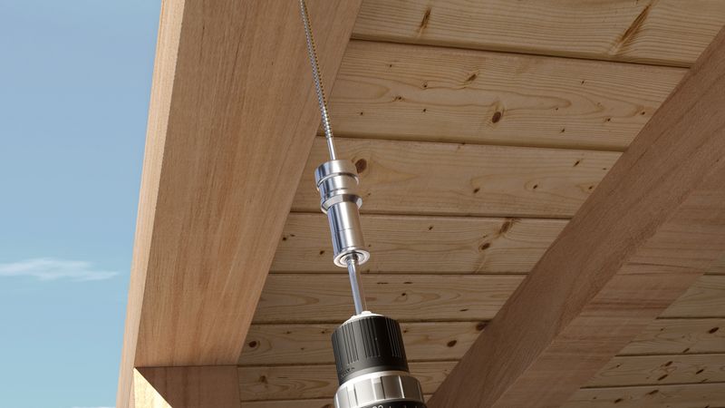 Ein Akkuschrauber bohrt ein Loch in eine Holzdecke.