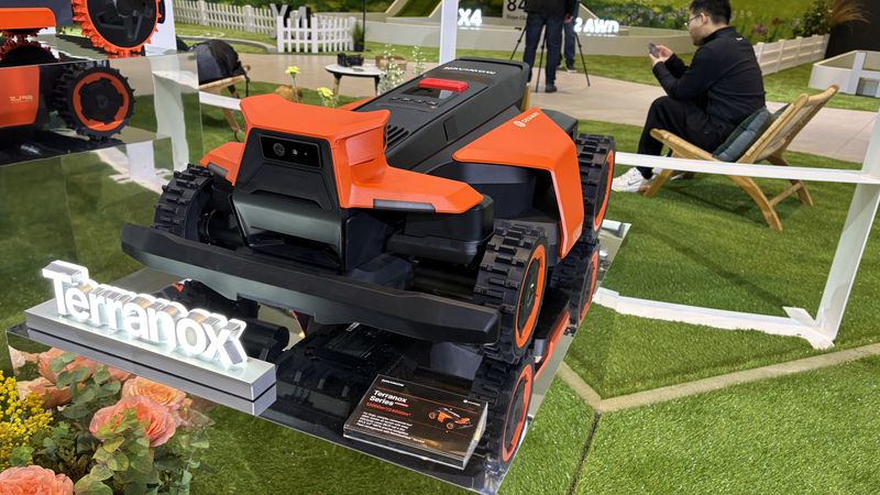 Ein moderner, orangefarbener Roboterrasenmäher der Marke Terranox auf einer Ausstellung.