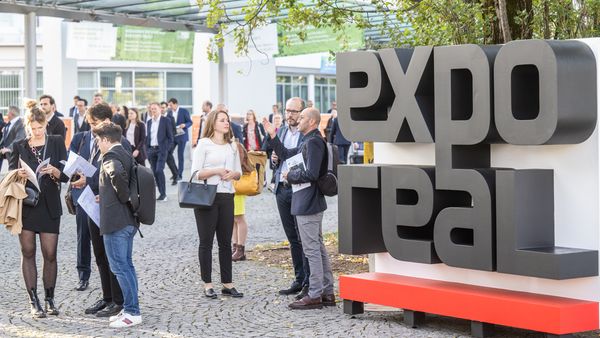 Besucher und Aussteller auf der Expo Real Messe in München vor dem Expo Real Schild