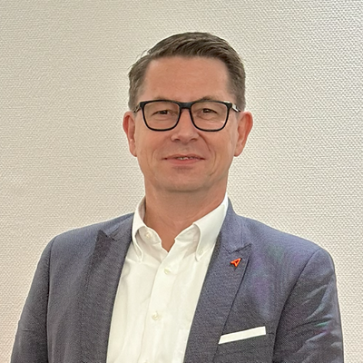 Ein Mann mit Brille in einem Anzug vor einem neutralen Hintergrund.