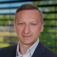 Ein Porträt eines Mannes in einem Anzug vor einem verschwommenen Hintergrund.