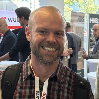 Zwei Personen halten einen großen Bilderrahmen mit der Aufschrift "EASTWOOD" auf einer Messe.