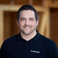 Porträt eines lächelnden Mannes in einem schwarzen Polohemd.