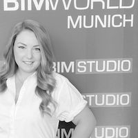 Elvan Ötztürk steht vor einem BIMWORLD MUNICH Banner und lächelt in die Kamera.