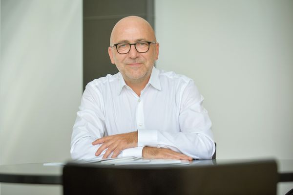 Günter Ruhe sitzt lächelnd an einem Tisch.