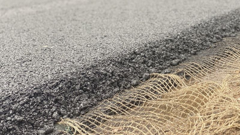 Eine Nahaufnahme von frischem Asphalt mit einem integrierten Sensorgewebe.