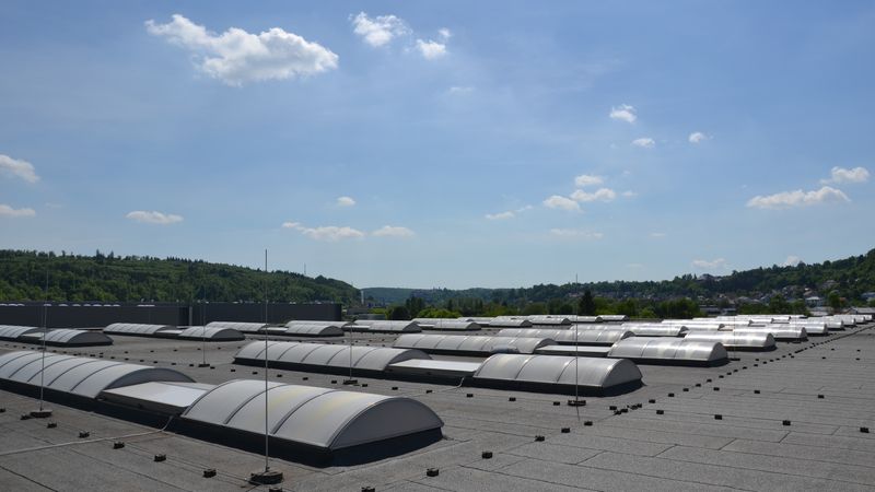 Ein großes Flachdach mit mehreren Oberlichtern unter einem klaren blauen Himmel.
