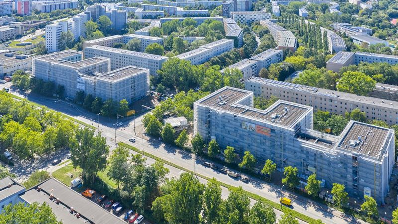 Luftaufnahme von Wohngebäuden in Berlin, umgeben von Bäumen und Straßen.