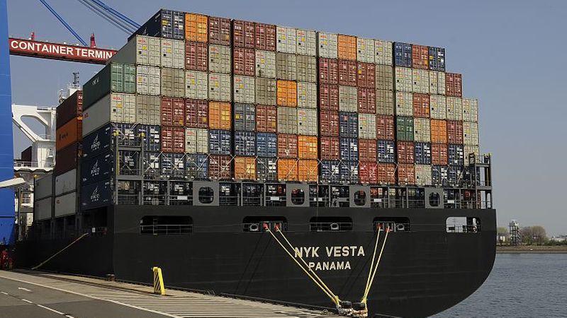 Ein großes Containerschiff im Hafen, beladen mit zahlreichen bunten Containern.