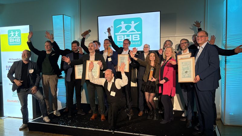 Eine Gruppe von Menschen feiert den Gewinn des BHB BranchenAwards auf einer Bühne.