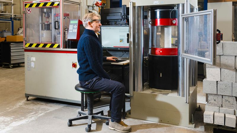 Ein Techniker führt in einem Labor eine Materialprüfung an einer Maschine durch.