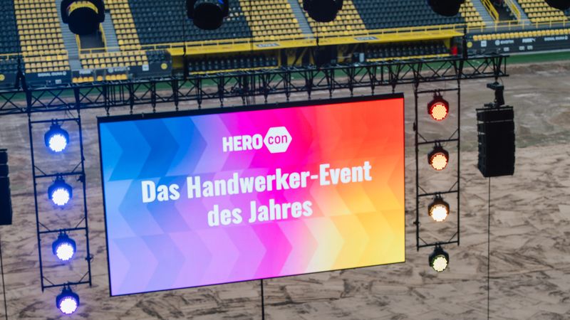 Eine Bühne im Stadion mit einem großen Bildschirm, der das Handwerker-Event des Jahres ankündigt.