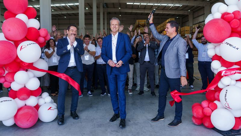 Feierliche Eröffnung einer Lagerhalle mit einer Gruppe von Menschen, die applaudieren und Luftballons in Rot und Weiß.