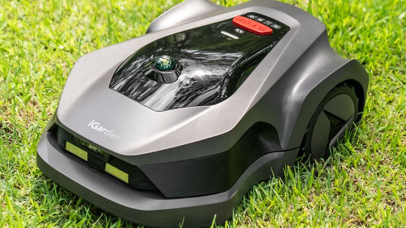 Ein moderner Rasenmähroboter auf einem grünen Rasen im Einsatz.