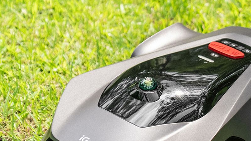 Ein moderner Rasenmähroboter auf einem grünen Rasen im Einsatz.