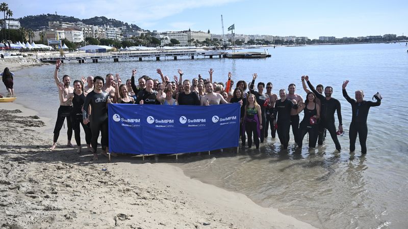 Eine Gruppe von Schwimmern steht am Strand und posiert für ein Foto.