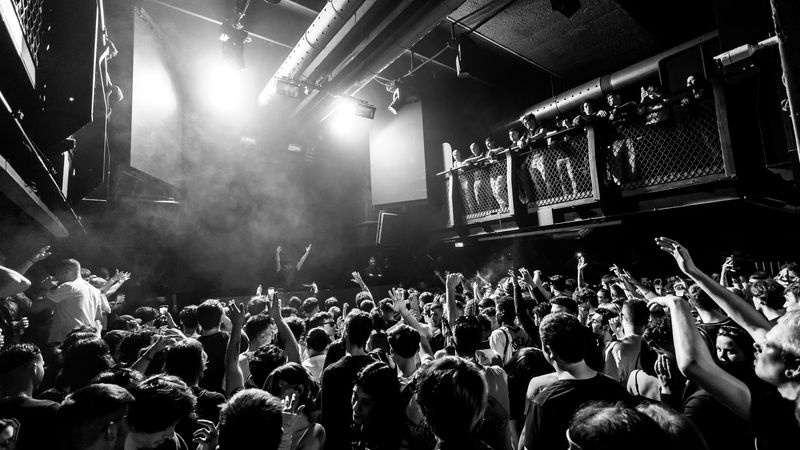 Eine große Menschenmenge tanzt und feiert in einem Nachtclub mit lebendiger Atmosphäre.
