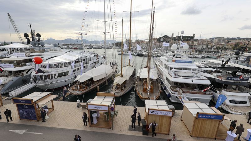 Eine Reihe von Luxusyachten im Hafen, umgeben von Besuchern und Ausstellungsständen.