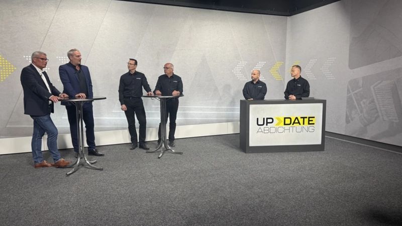 Eine Diskussionsrunde mit sechs Personen in einem Studio, das mit dem Logo "UPDATE ABDICHTUNG" dekoriert ist.