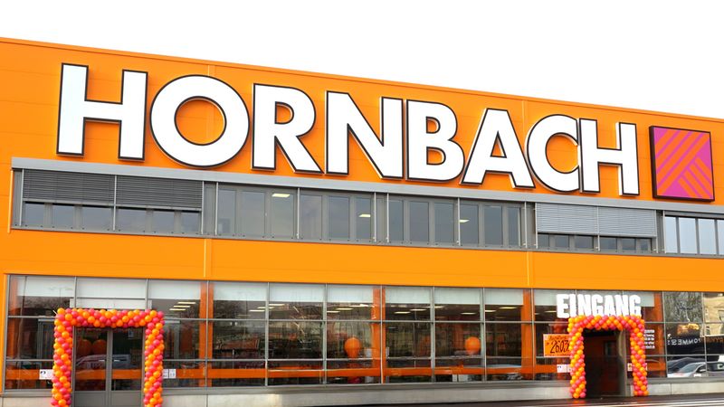 Die Fassade eines Hornbach-Baumarkts mit dem markanten orangefarbenen Logo und dekorierten Eingängen.
