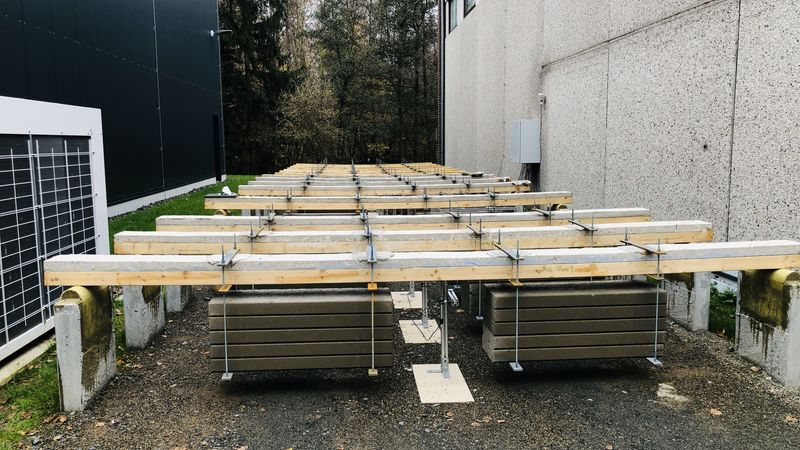 Geklebte Brettschichtholz-Beton und Holz-Faser-Kunststoff-Verbundplatten, umgeben von Bäumen und Betonwänden.