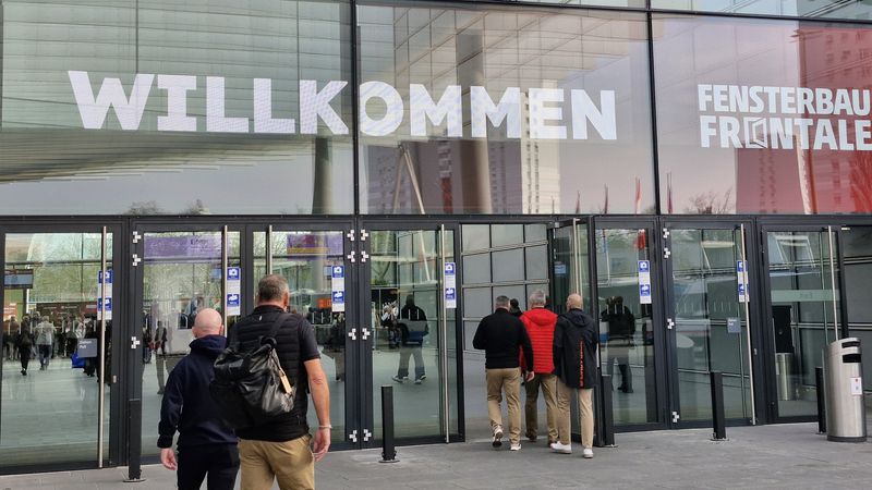 Besucher betreten den Eingang einer Messehalle mit dem großen Schriftzug "WILLKOMMEN".