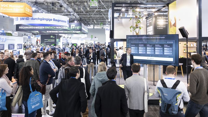 Ein Vortrag über digitale Lösungen auf einer Messe, bei dem viele Menschen aufmerksam zuhören.