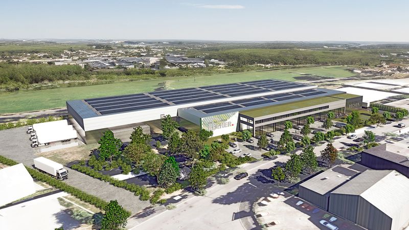 Luftaufnahme eines modernen Logistikzentrums mit Solarpanels auf dem Dach und umgebender Landschaft.