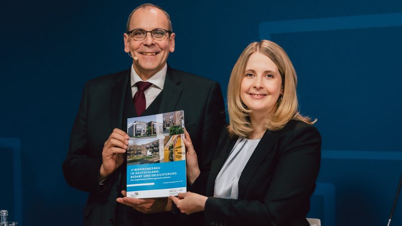 Zwei Personen präsentieren ein Buch über Wohnungsbau in Deutschland.