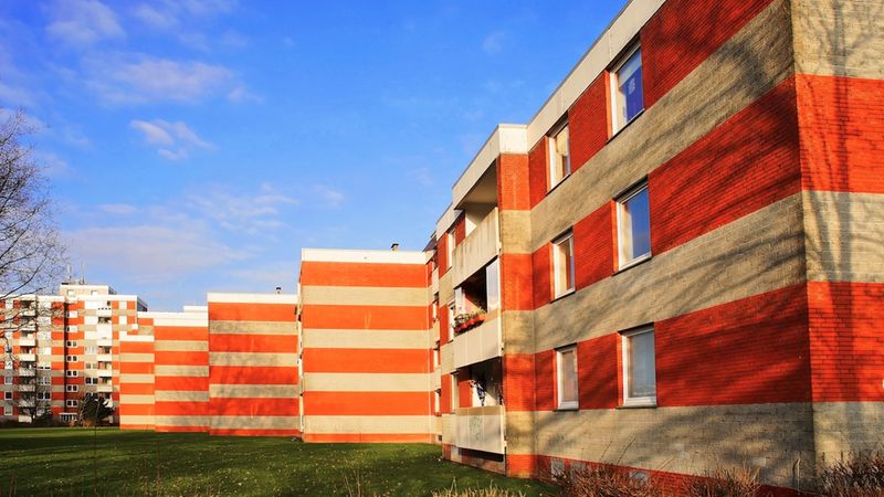 Geschosswohnungsbauten aus Ziegelsteinen mit klaren Linien und großen Fenstern unter einem blauen Himmel.
