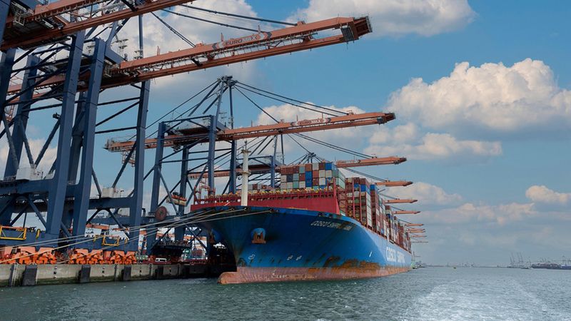 Ein großes Containerschiff wird von mehreren Hafenkränen im Hafen beladen.