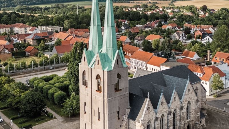 Eine beeindruckende Kirche mit Zwillingstürmen in einer malerischen Kleinstadtlandschaft.