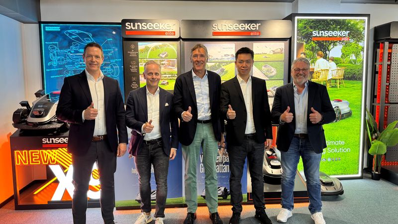 Eine Gruppe von fünf Männern steht vor einer Sunseeker Präsentationswand und lächelt in die Kamera.